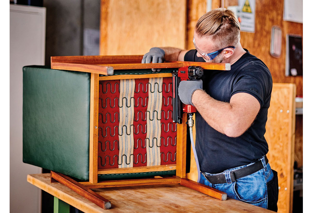 Απεικονίζεται άνδρας να χρησιμοποιεί τον αεροσυμπιεστή για εργασία σε μια καρέκλα.